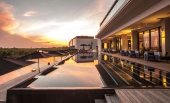 a large outdoor swimming pool surrounded by a deck , with a beautiful sunset in the background at Nizuc Resort & Spa