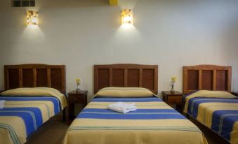 a hotel room with three beds , one on the left , one in the middle , and one on the right at Donaji