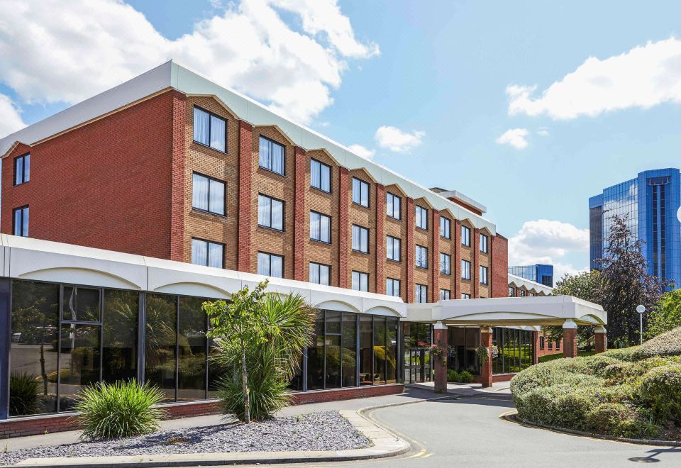 a large brick building with a red brick facade , situated in front of a body of water at Mercure Telford Centre Hotel