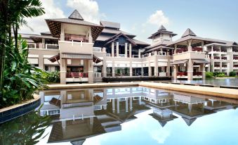 a large , two - story building with a pool in front of it , surrounded by lush greenery at Le Meridien Chiang Rai Resort, Thailand