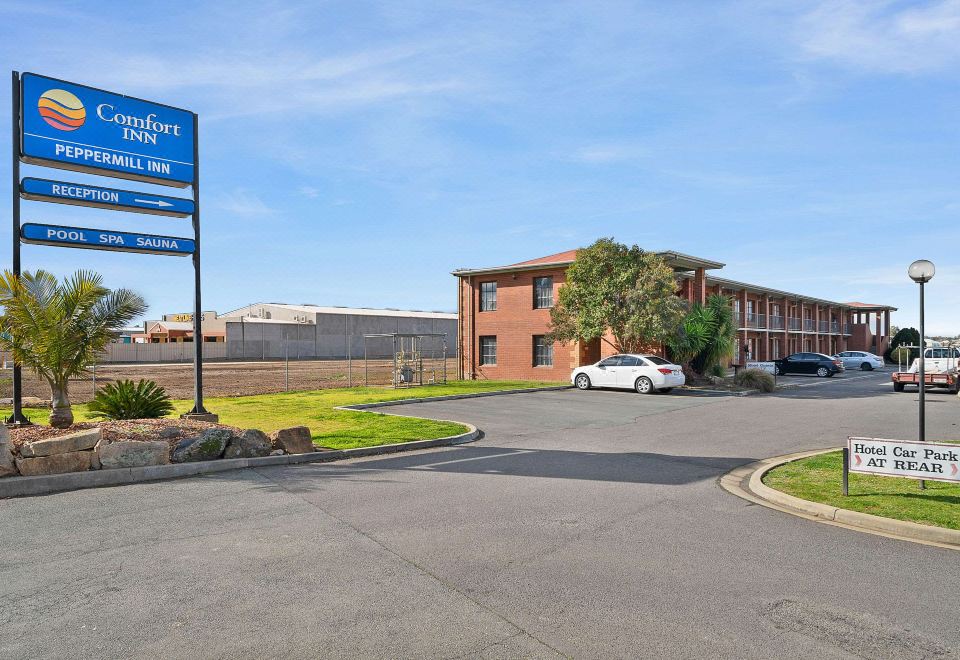 an exterior view of a motel with a large parking lot in front of it at Peppermill Inn Motel