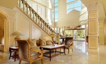 a luxurious living room with large windows , wooden furniture , and a staircase leading to an upper level at The Heritage