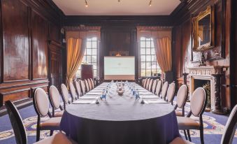 a long table with blue tablecloths and white chairs is set up in a room with wooden walls at Coombe Abbey Hotel