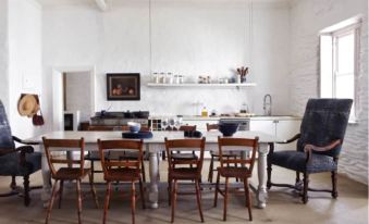a dining room with a large wooden dining table surrounded by chairs , and a kitchen in the background at The White House
