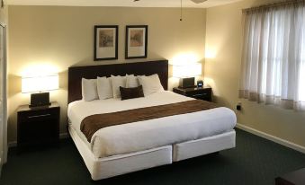 a large bed with white sheets and a brown blanket is in a hotel room at Beau Rivage Golf and Resort