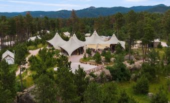 aerial view of a group of tents set up in a wooded area , surrounded by trees and mountains at Under Canvas Mount Rushmore