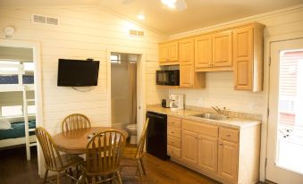 a kitchen with wooden cabinets , a sink , and a dining table set for two people at Indiana Beach Accommodations