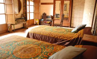 a cozy bedroom with two beds , each covered in colorful blankets , and a large mirror on the wall at La Casa de Alberto
