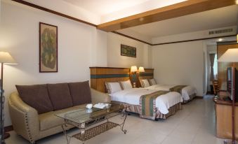 a hotel room with two beds , a couch , and a coffee table , all decorated in white and brown colors at Rainbow Hotel