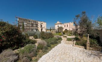 There is a garden consisting of two buildings and an open field in the middle, located adjacent to another building at Casino Doxi Stracca by BarbarHouse