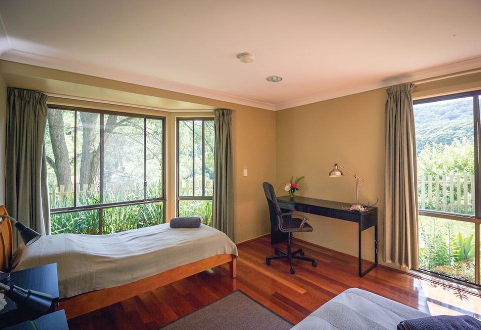 a bedroom with a bed , desk , and chair is shown with a view of the outdoors at Heart & Soul Retreats