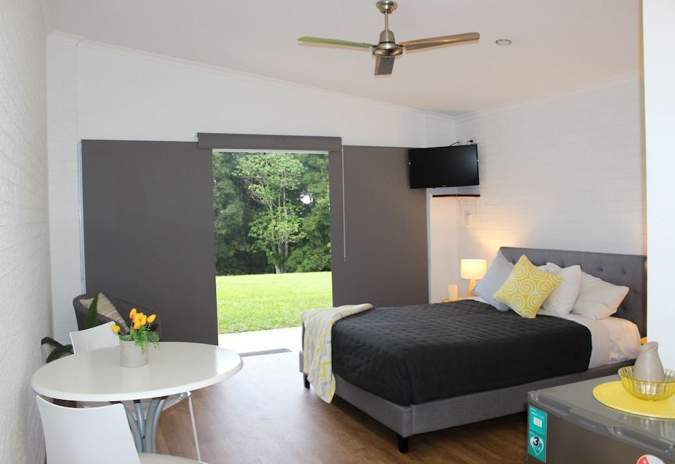 a modern bedroom with a large bed , a tv , and a sliding glass door leading to a patio at Ardeena