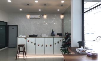a modern office reception area with a white marble wall and a wooden counter , decorated for the holiday season at Klongyai Center