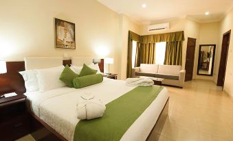 a large bed with a white and green comforter is in the middle of a room at Golden Bean Hotel