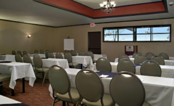 a large , empty conference room with multiple tables and chairs , a whiteboard , and a chandelier hanging from the ceiling at Red Lion Hotel Port Angeles Harbor
