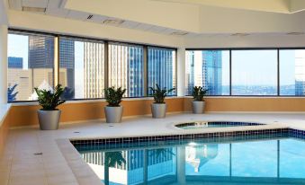 an indoor swimming pool surrounded by large windows , with a city view visible outside the window at Sheraton Grand Seattle