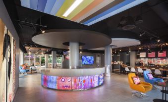 a modern restaurant with a colorful mural on the ceiling and a round bar in the middle of the room at Aloft Miami Dadeland