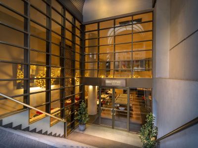 a modern hotel entrance with large windows and a staircase leading up to the lobby at Ibis Melbourne Hotel and Apartments