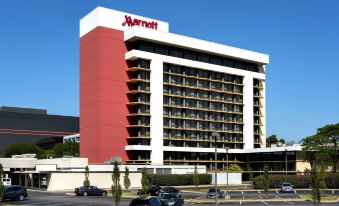 a large hotel with a red and white exterior , surrounded by trees and a road at Marriott Saddle Brook