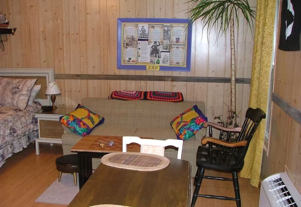 a cozy living room with wooden walls , a couch , a dining table , and a kitchen area at Lamplight Inn