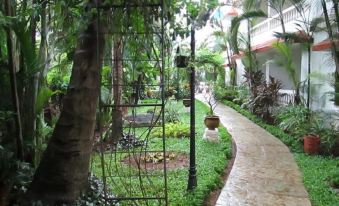 a lush green garden with a brick path leading through it , surrounded by tall trees at Casablanca