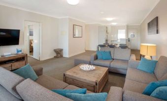 a living room with a gray couch , wooden coffee table , and a dining area in the background at Broadwater Resort Como