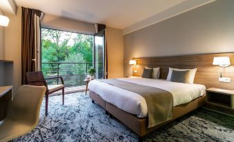 a large bed with white sheets and a wooden headboard is in a room with a chair , lamp , and sliding glass doors leading to a at Utopia Hotel - Art & Nature Hotel