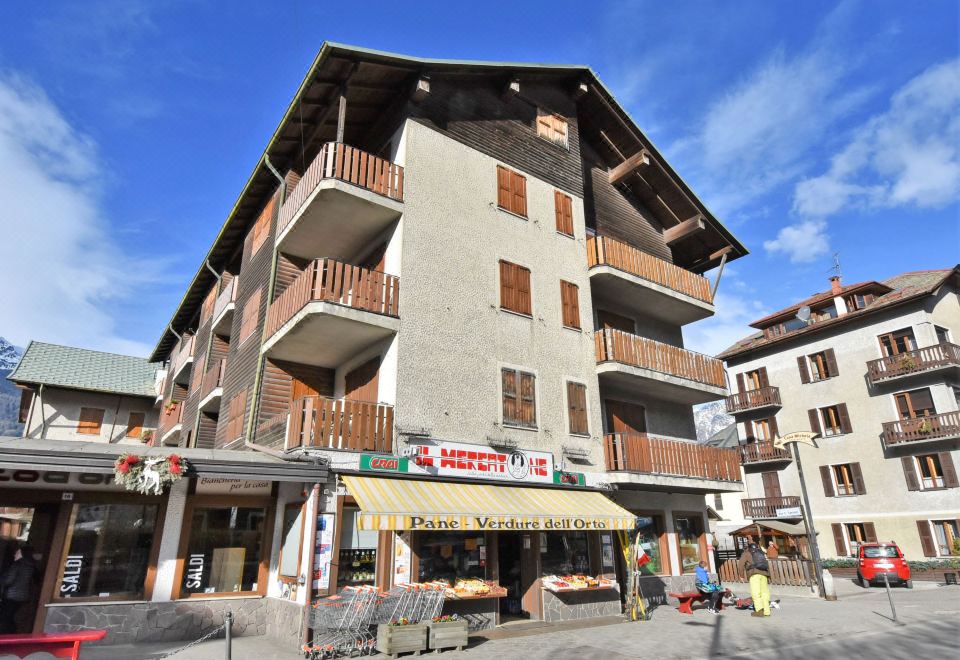 a large building with multiple balconies and a storefront , located in a city setting with shops and restaurants at San Anton