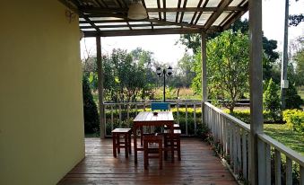 a wooden deck with a dining table and chairs , surrounded by lush greenery and a swimming pool at Rainbow Resort