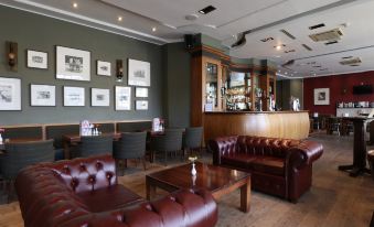 a bar with various seating options , including couches and chairs , as well as a dining table and chairs at Columba Hotel Inverness by Compass Hospitality