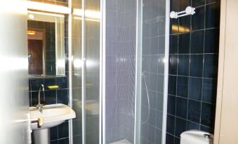 a bathroom with a glass shower door , black tiled walls , and a white sink on a pedestal at Antigua