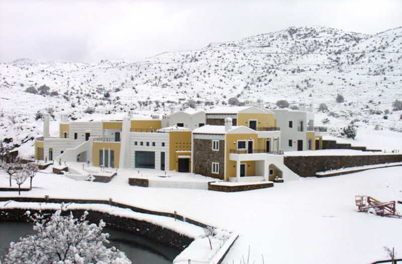 a snow - covered hillside with several houses , some of which have snow on their roofs , under a cloudy sky at Delina Mountain Resort