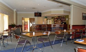 a dining room with several tables and chairs , as well as a television mounted on the wall at Boulevard Lodge Bundaberg