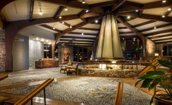 a large room with a stone fireplace and a wooden beam ceiling , creating an elegant atmosphere at Lodge of Four Seasons Golf Resort, Marina & Spa