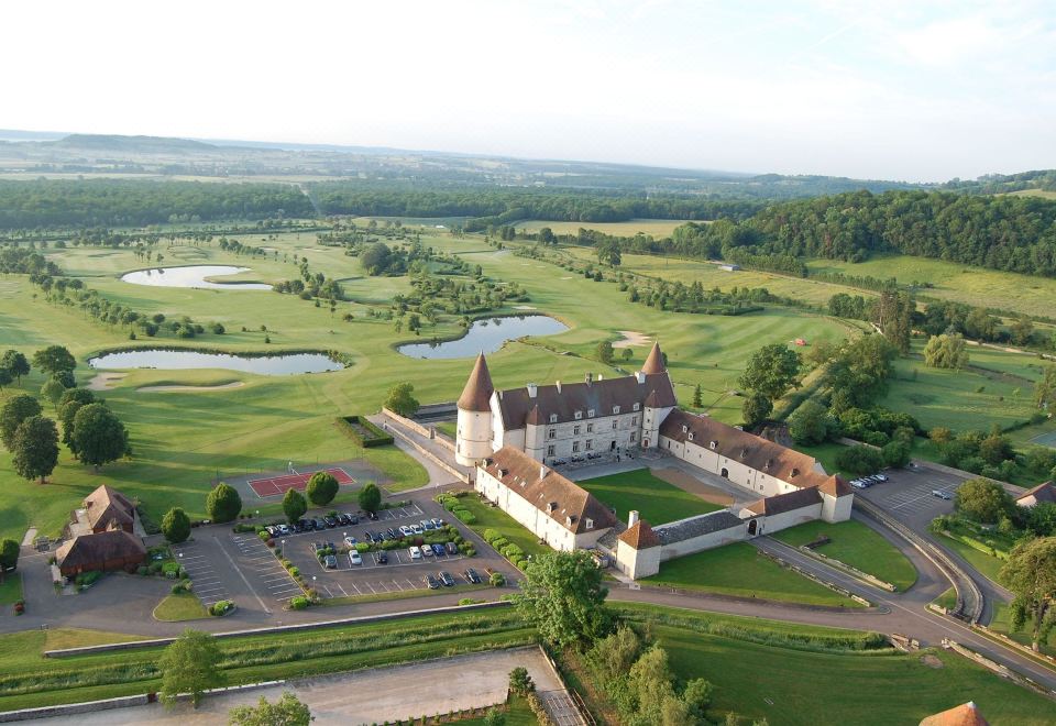 aerial view of a castle surrounded by a golf course , with a golf course in the background at Hôtel Golf Château de Chailly