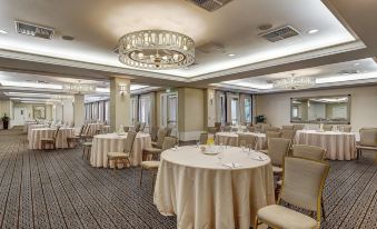 a large , well - lit banquet hall with numerous round tables and chairs arranged for a formal event at El Prado