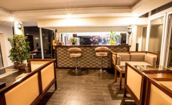 a modern bar with wooden floors , comfortable seating , and a large counter filled with liquor bottles at Gold Hotel Hue