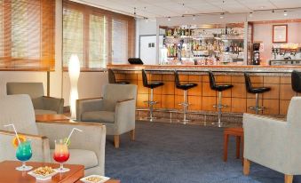 a bar area with several chairs and couches , as well as a dining table in the background at Novotel Tours Centre Gare