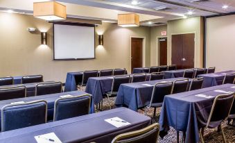 a conference room with multiple rows of chairs arranged in a semicircle , and a projector screen mounted on the wall at Cambria Hotel Appleton