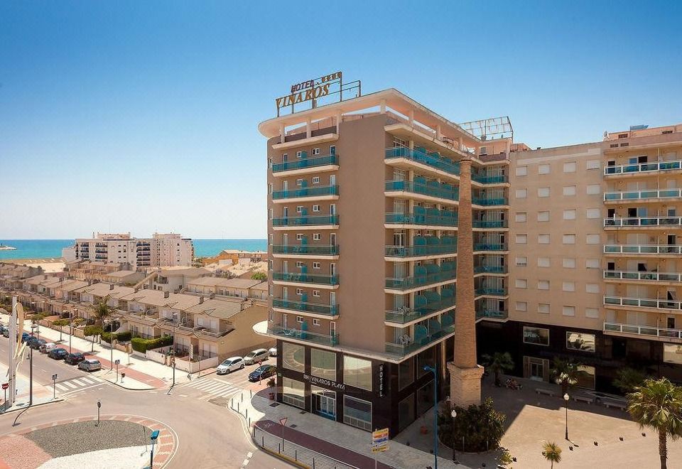 a tall building with a restaurant on the ground floor , located near a beach and a city skyline at Estudios RH Vinaros