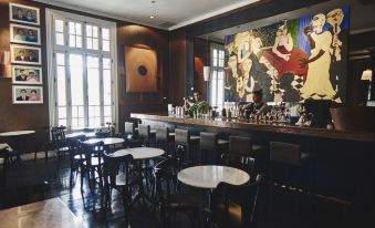 a modern bar with black and white chairs and tables , a mural on the wall , and large windows at Hotel B