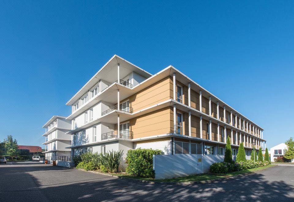 a large , modern building with multiple floors and balconies under a clear blue sky at Comfort Suites Pau Idron