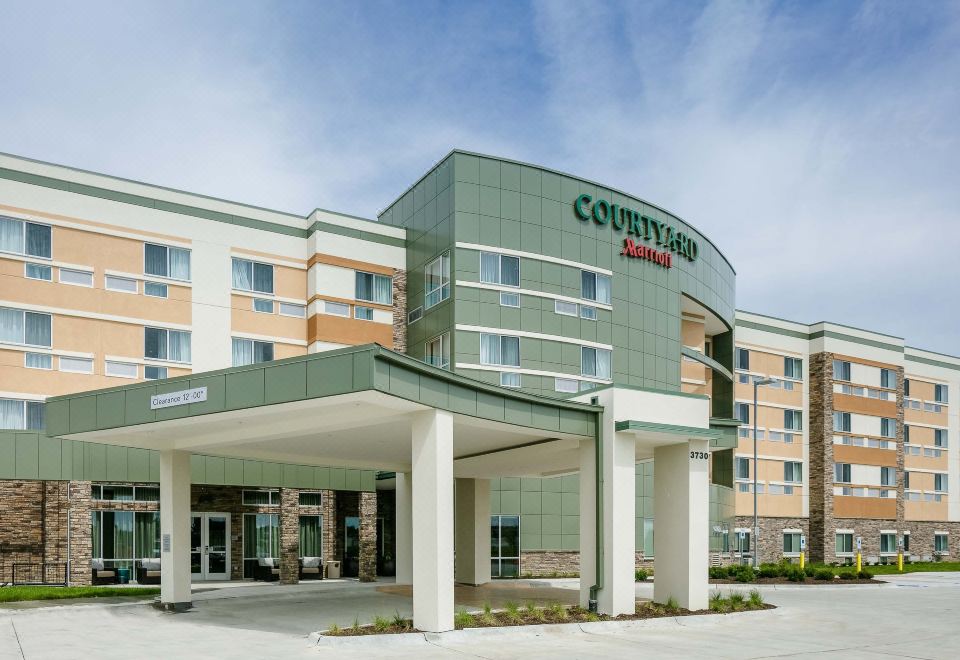 a courtyard by marriott hotel with its green and white exterior , set against a blue sky at Courtyard Omaha Bellevue at Beardmore Event Center