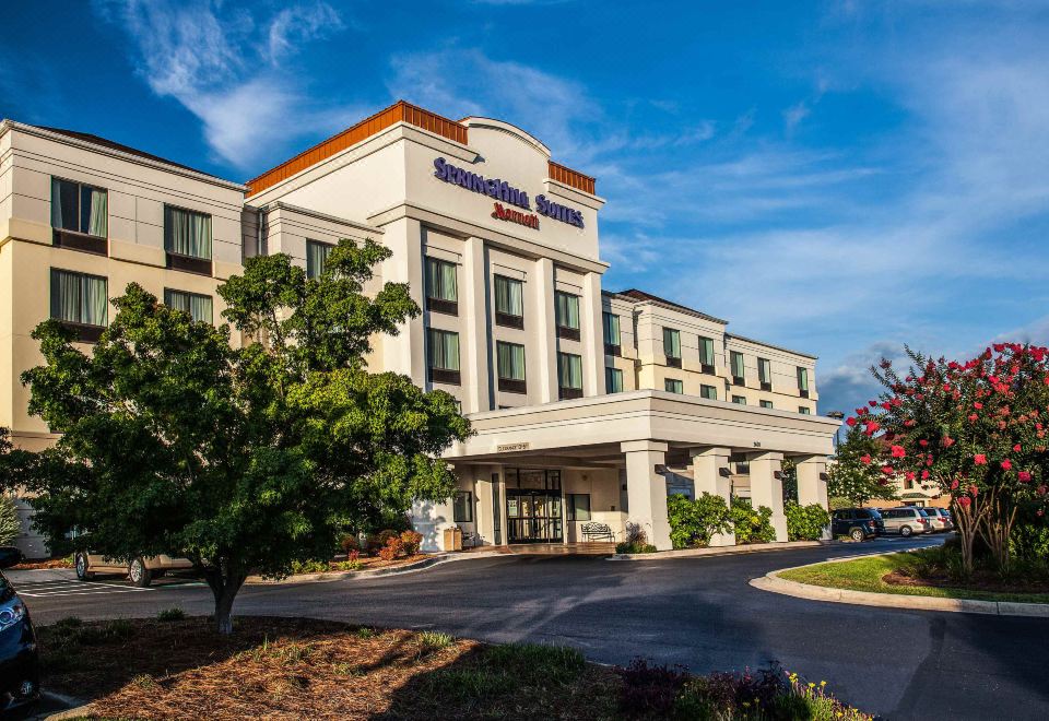 a large hotel building with a tree in front of it , under a clear blue sky at SpringHill Suites Florence