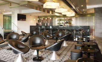 a modern bar with black chairs and stools arranged around a central bar area , creating a comfortable atmosphere for patrons at Crowne Plaza London - Kingston