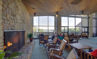 a large room with a fireplace and several people sitting in chairs near tables and windows at Deer Creek Lodge & Conference Center