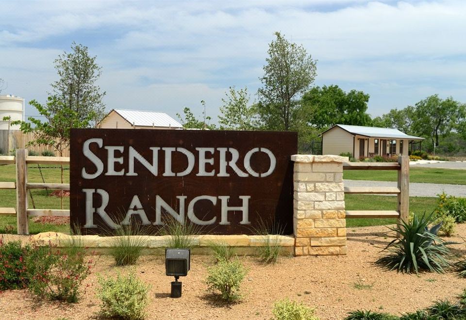 a large sign for sendero ranch is displayed in front of a residential area with houses at Sendero Ranch