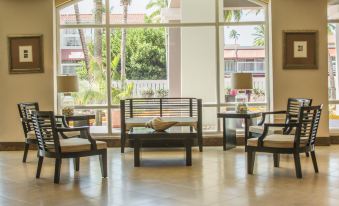 a modern living room with large windows , wooden furniture , and comfortable seating arrangements , surrounded by palm trees at Aquarius Vacation Club at Dorado del Mar