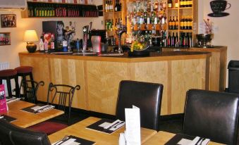 a dining room with a wooden bar counter and chairs , as well as a dining table with chairs at The Kings Head Hotel