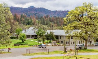 a large , two - story house with a flat roof and multiple balconies is surrounded by trees and mountains at Sierra Sky Ranch, Ascend Hotel Collection